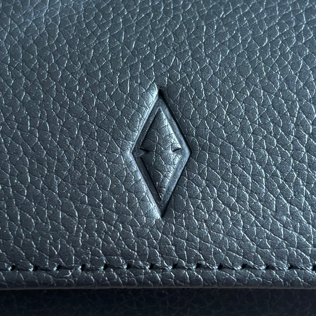 Close up of ASCATI top grain leather showing the debossed logo and natural leather grain